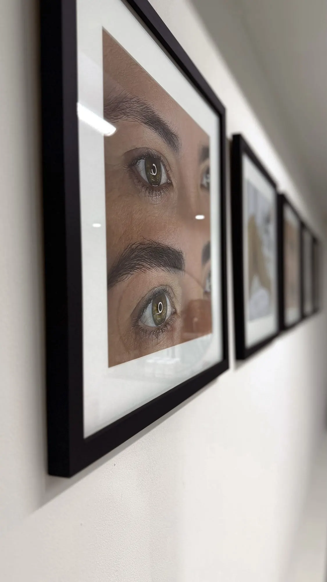 Cuadros con fotografías de cejas en la pared del estudio
